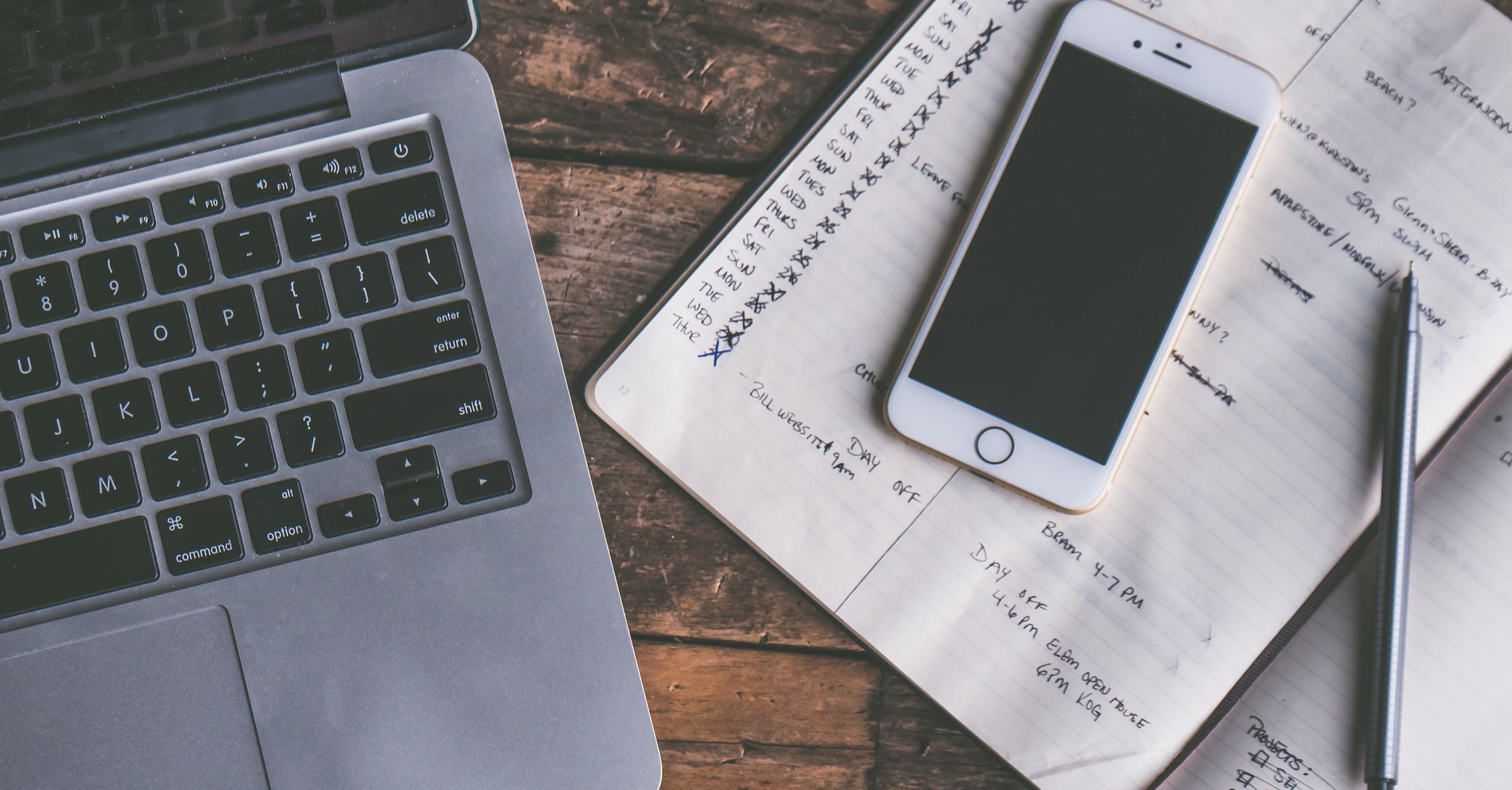 Laptop, phone and notebook on a desk for AI construction scheduling dashboard