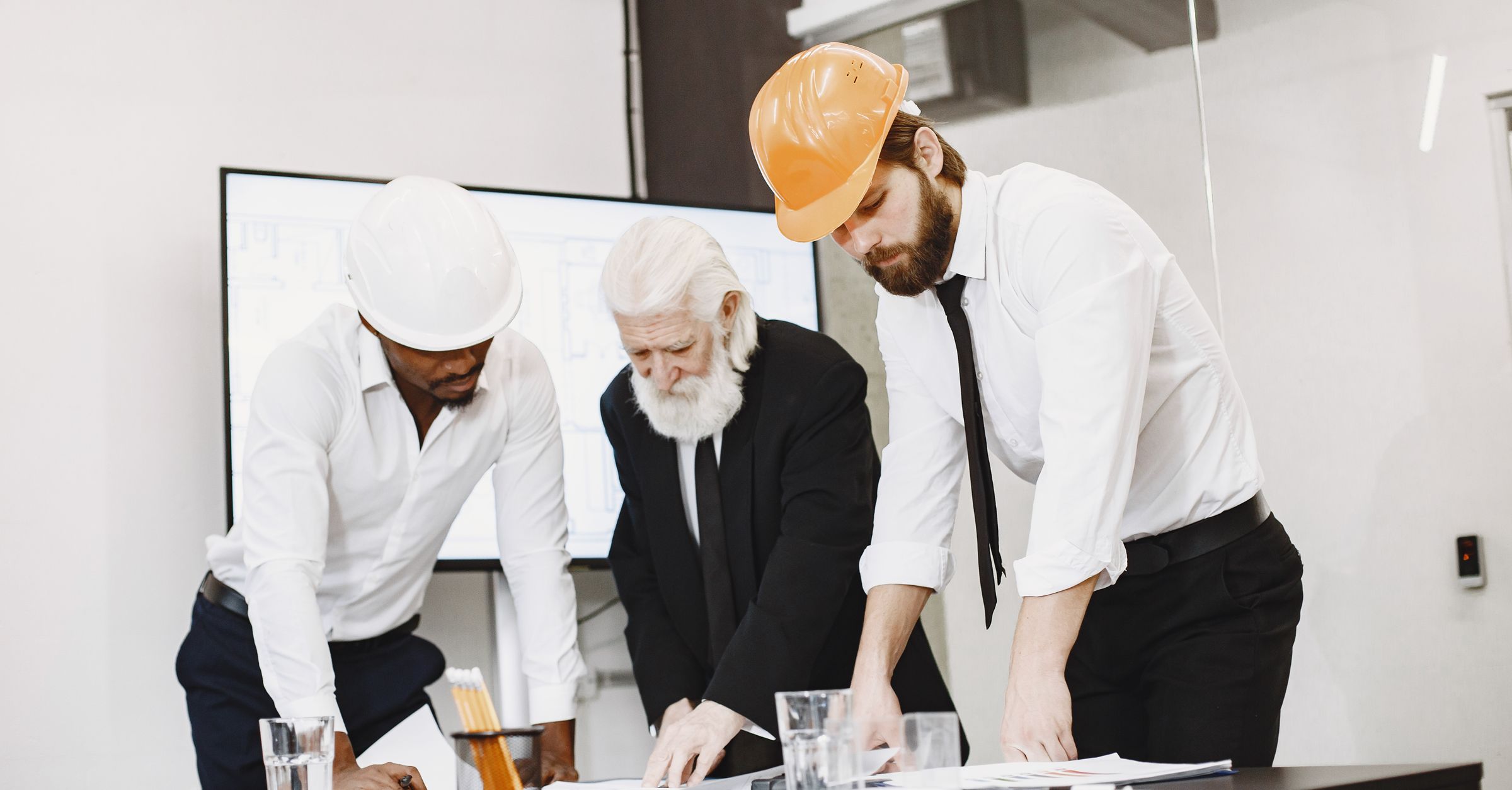 Architects and subcontractors reviewing construction blueprints in an office